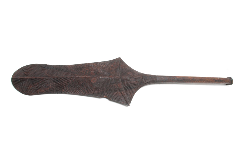 Paddle club of dark wood, relatively light in weight. The blade long and rounded at the top.
