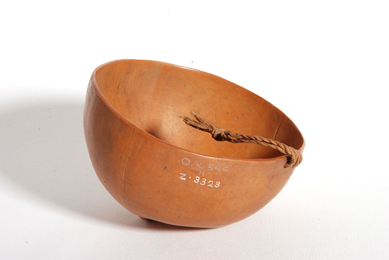 Coconut bowl, orange in colour, with a twisted coir cord attached at one side.
