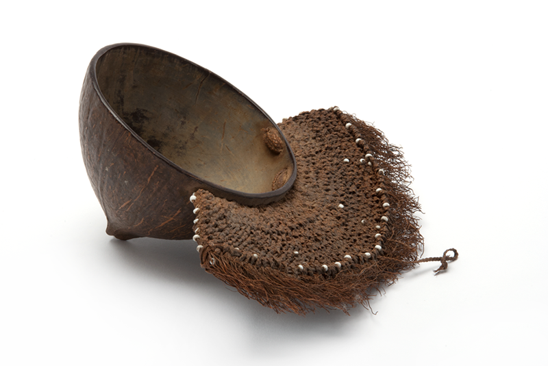Dark brown coconut cup with woven coir handle, which forms a large quarter circle, with small white glass beads woven into it.