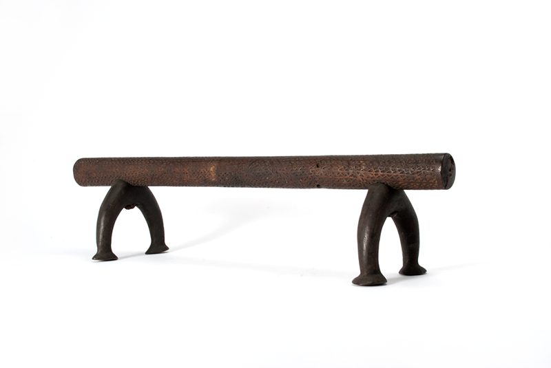 Dark brown headrest with a circular wooden post, standing on two rounded metal legs/stands
