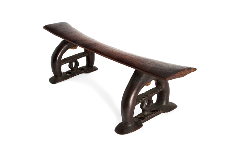 Headrest of wood with very dark-coloured legs and a lighter brown bar.