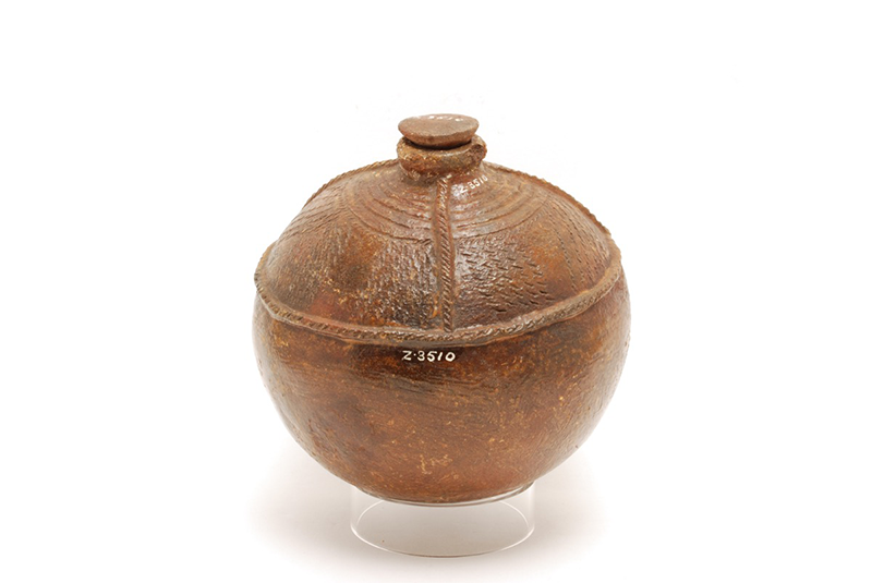Glazed ceramic water pot. Globular in shape with vertical and diagonal notches along the top half of the pot.