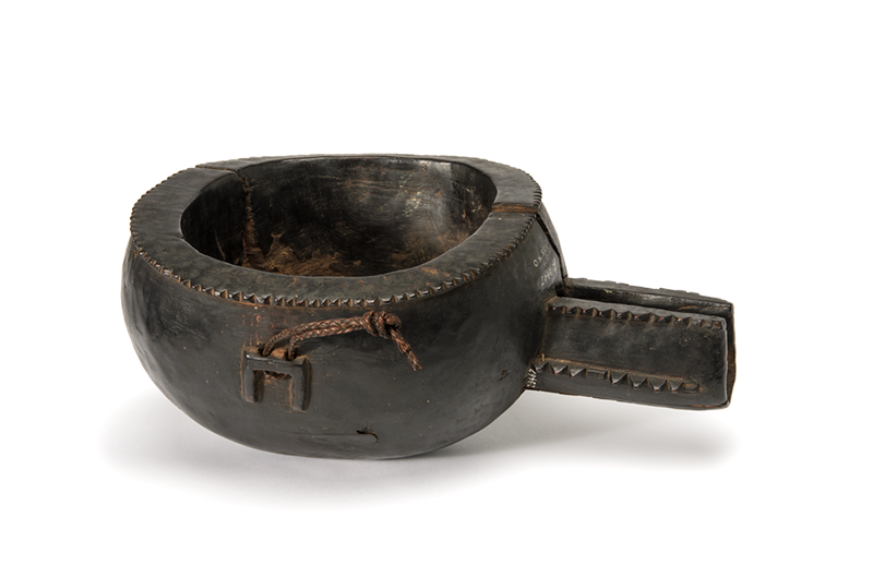 Very dark brown vessel with a pouring spout. A small inverted u-shaped lug is carved on the side. 
