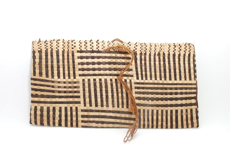 Rectangular woven satchel in natural shades, with a chequerboard design with horizontal and vertical line patterns. A cord hangs from the middle for holding or wrapping.