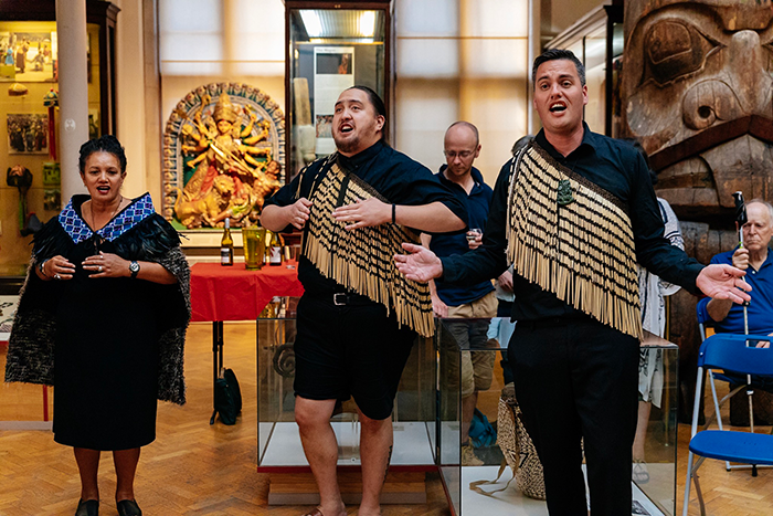 Two men and a woman, dressed in traditional pacific dress, perform in the MAA gallery.