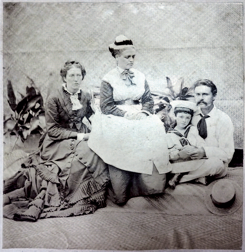 Black and white photograph of three adults and a child, posing in seated positions.