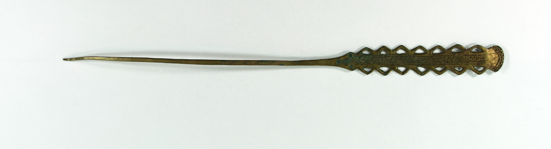  A brass hairpin with jagged edges around the top section. The jagged protrusions have negative triangular spaces within.