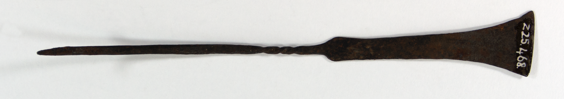 Iron hairpin with a thin handle. The upper shaft is cylindrical and twisted, and with a flat flared edge.