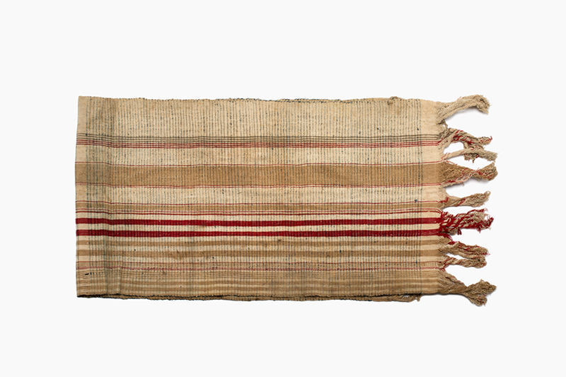 Striped piece of cloth in beige, brown and red. There are long fringes on both short edges.