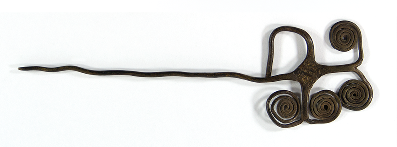 Brass hairpin designed in a tree shape, with four spirals and one bent extension at the head of the pin. Deep brown in colour.