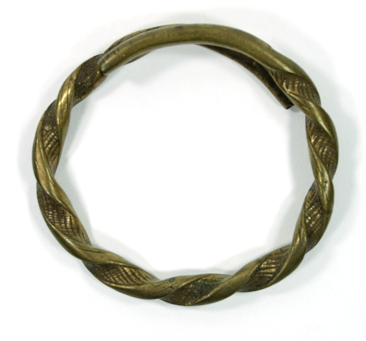 Bracelet of wrought brass, twisted with incision motifs, with ends overlapping.