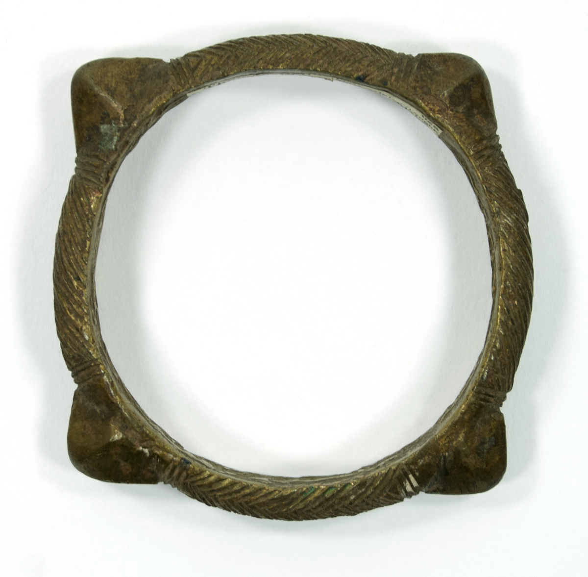 Bracelet wrought brass with four pointed knobs between which are incised patterns, two zig-zag, two oblique shapes.