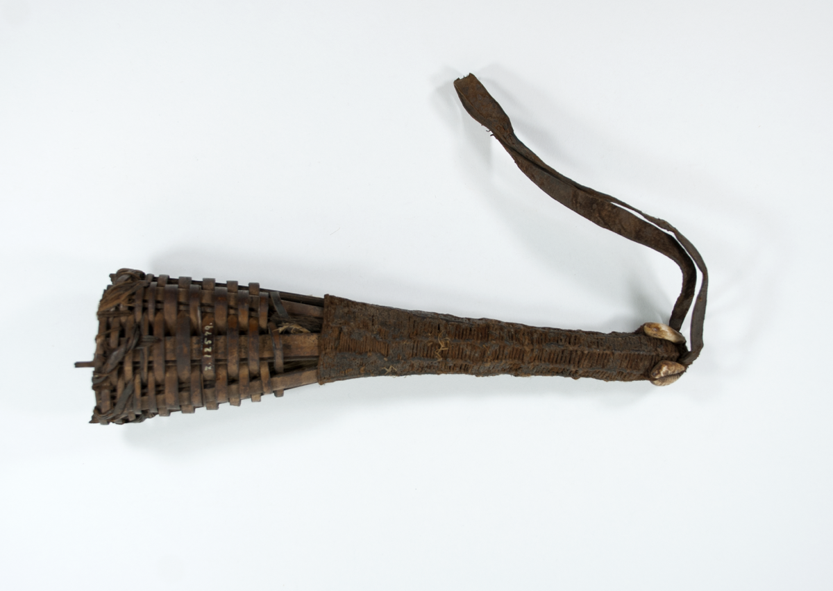 Basketwork horn with feathers inside open end. The other end is enclosed, covered with string, and ornamented with two cowrie shells along with a leather strap. 