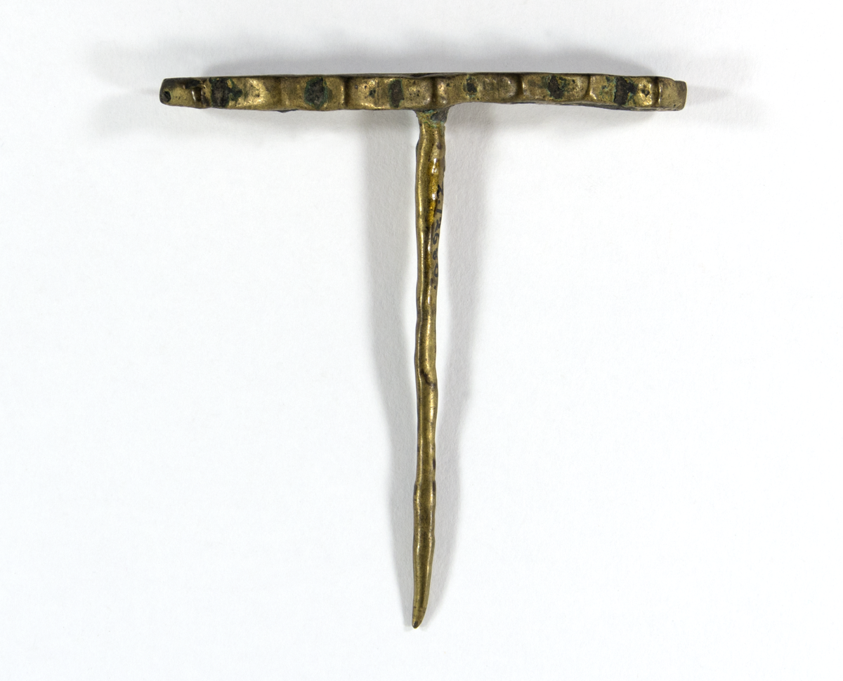 T-shaped hairpin with an undecorated shaft. The T-bar is decorated with numerous circular impressions on top which extend a bit to the sides; gives it a jagged appearance.