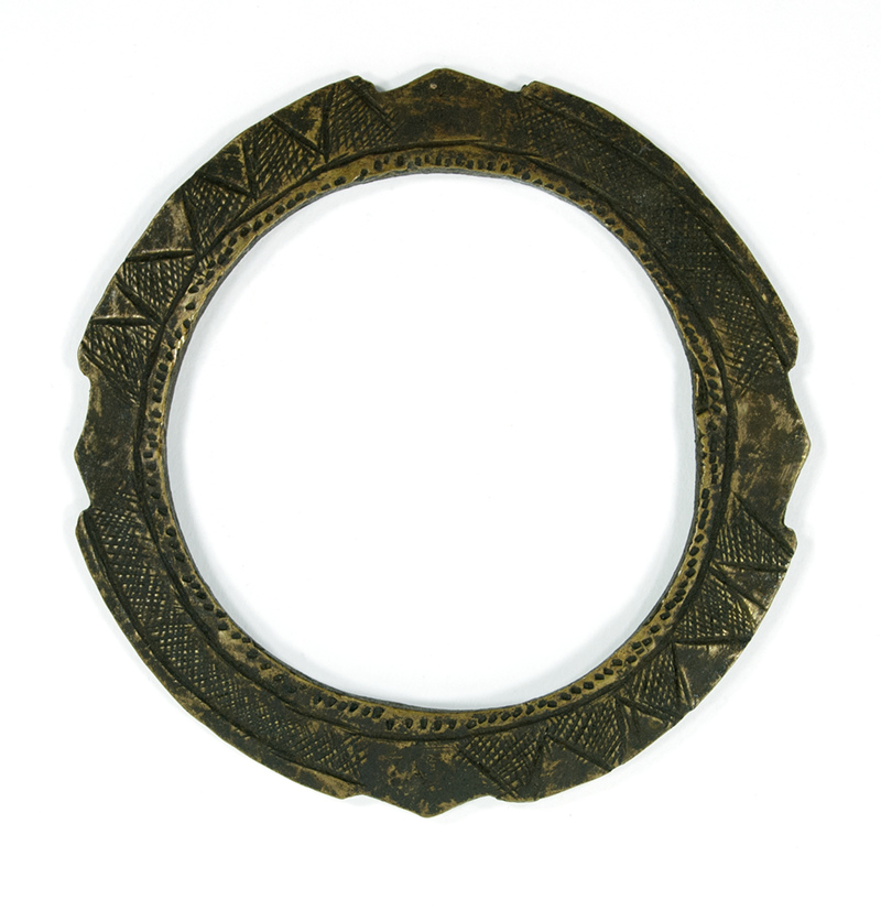  Bracelet of wrought brass, flat with jagged edge, and fine incised pattern on both sides.