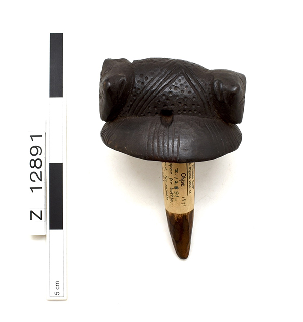 Carved wooden bottle stopper with a rounded top, and two back-to-back animals. Seen side-on, next to a measurement guide showing it to measure around 150mm.