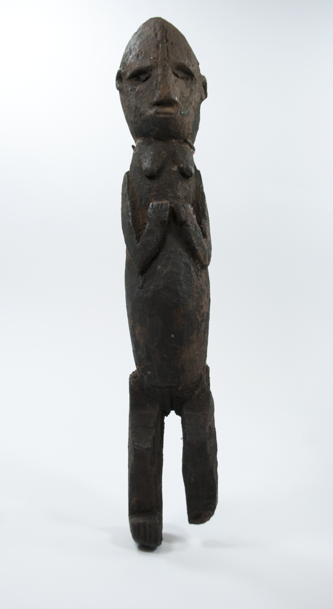 Standing female figure carved from wood. Hands on chest, short legs with bent knees.