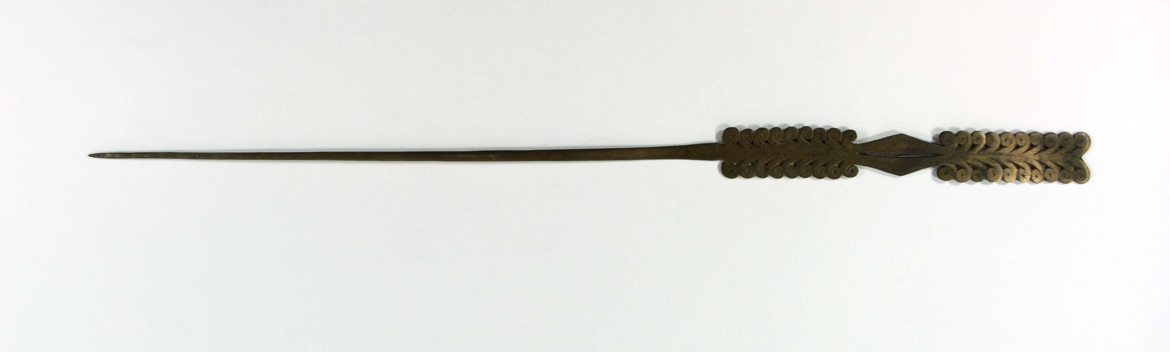 Brass hairpin with flat cross section; stacked scrolls turning away from the shaft. One part of the top seems discoloured or lighter, perhaps by light, although it looks pleasing.