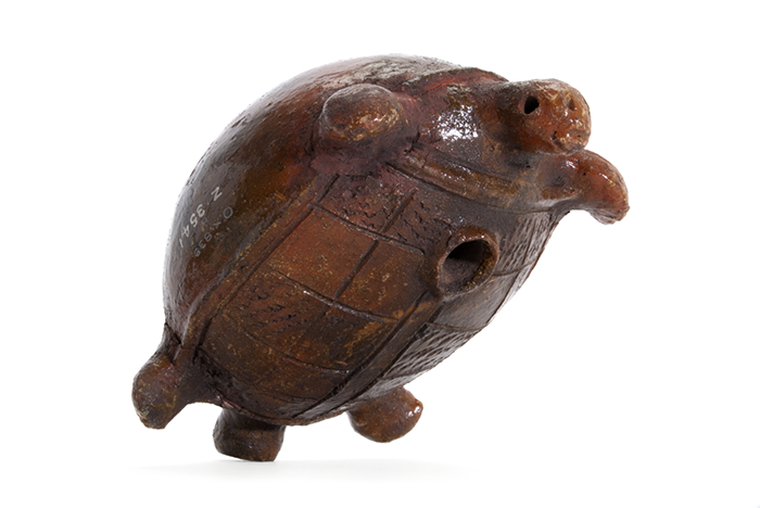 Small water pot in the shape of a turtle. There is a cylindrical spout in place of a tail, and a large circular hold on the stomach of the turtle.