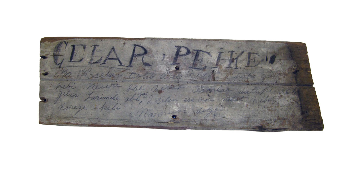 Board with words in black pencil or crayon. Reads, "No Koeker tebteb abele uteb a pako gaire kebi neure ese nerut Kimiar datupi abele gelar tarimele abi saz 2 selen ese nole netat mebege dorege ikeli Mamusi doge".