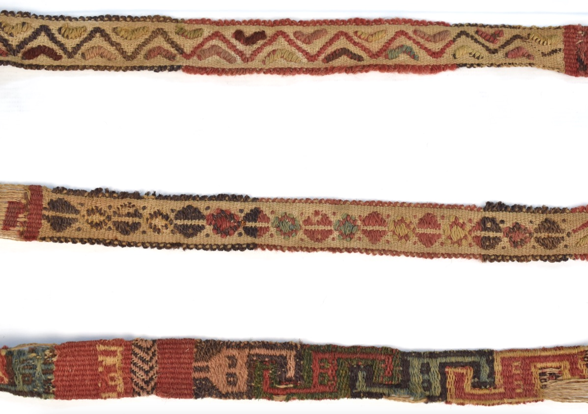 Three sections of a long, thin, woven textile. It is decorated with geometric patterns of zig-zags and triangles.