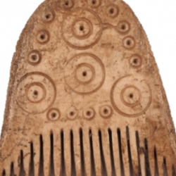 A rounded bone comb with narrow teeth. The body of the comb has circular detailing, smaller at the edge then four large circles interspersed throughout.