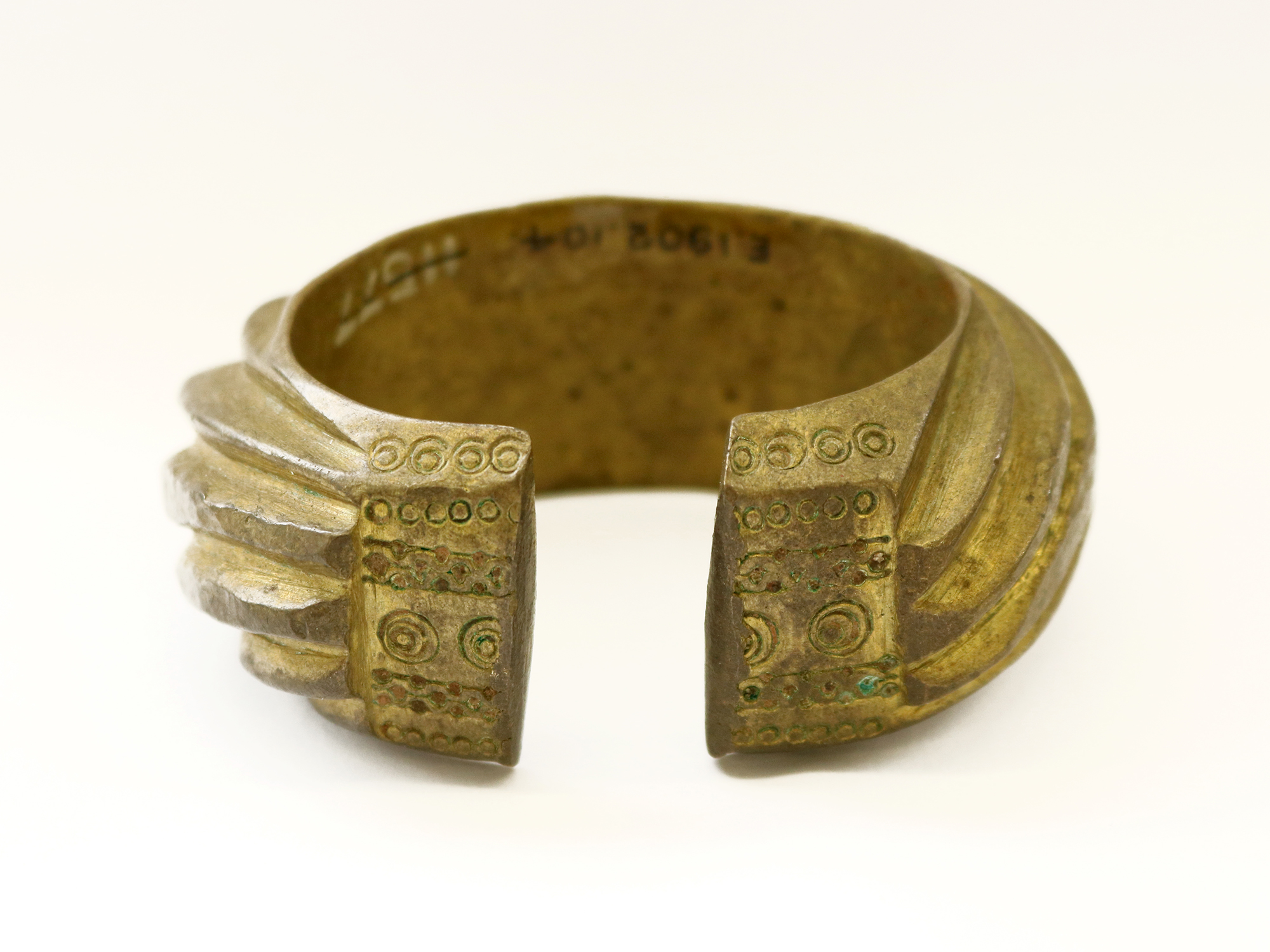 Heavy brass penannular bracelet composed of heavy convex band decorated with heavy slanting bands.