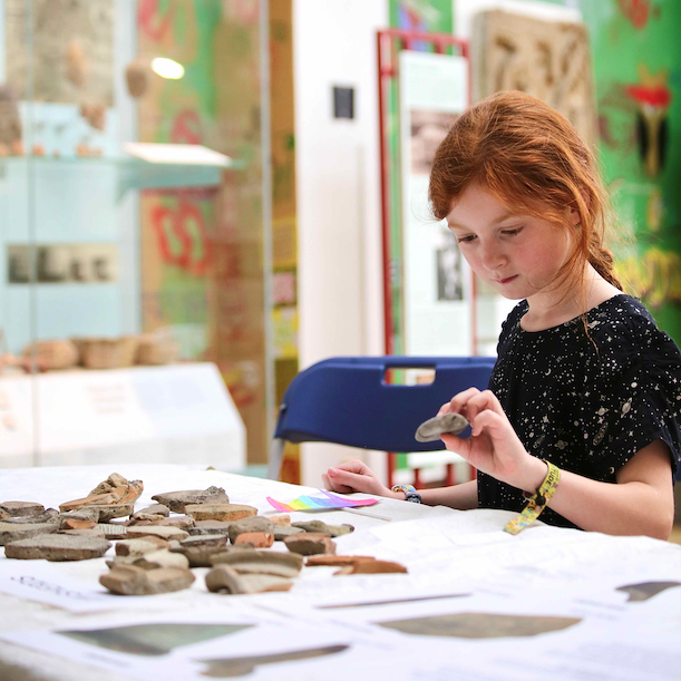 A young girl takes part in an object handling session trying to identify which are pieces of pottery and which are stones.