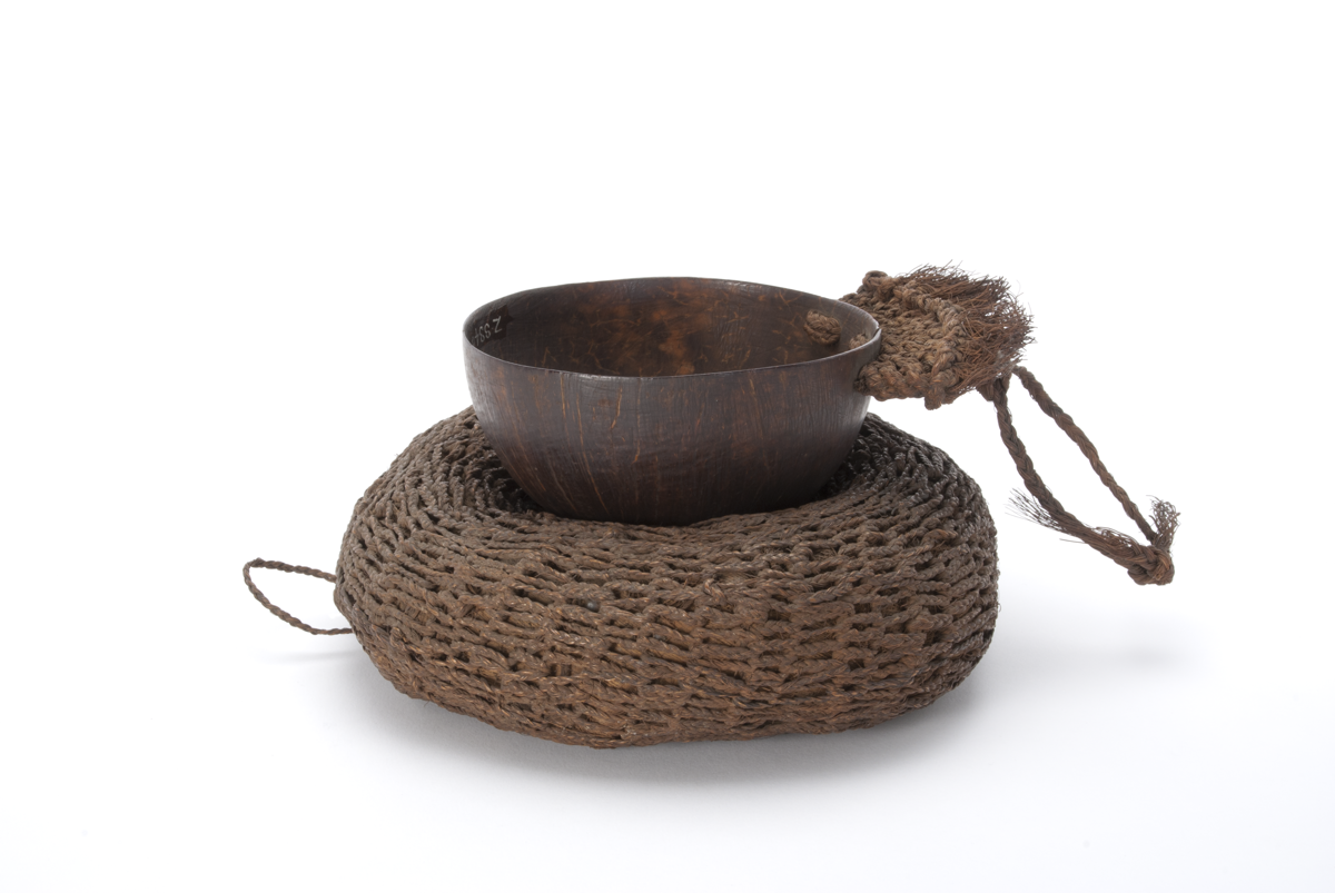 Half a coconut made into a cup, with a rounded woven stand.