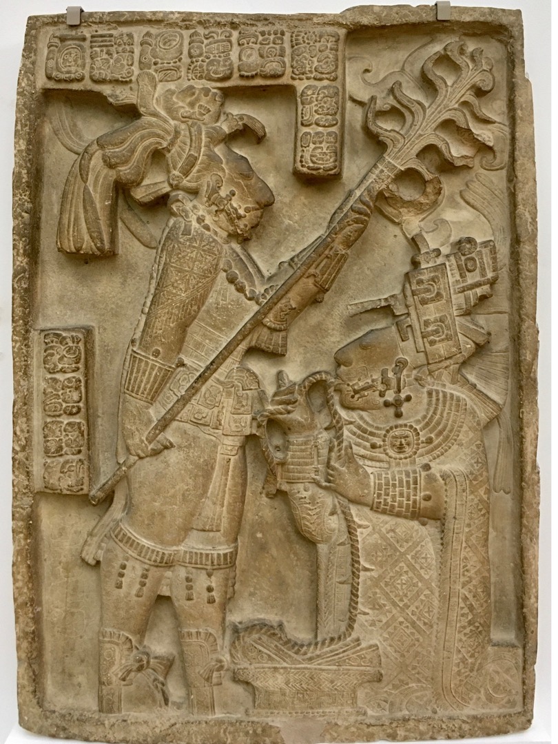 A stela detailing two figures engaged in a blood letting ceremony. They are wearing regal clothes and headdresses.