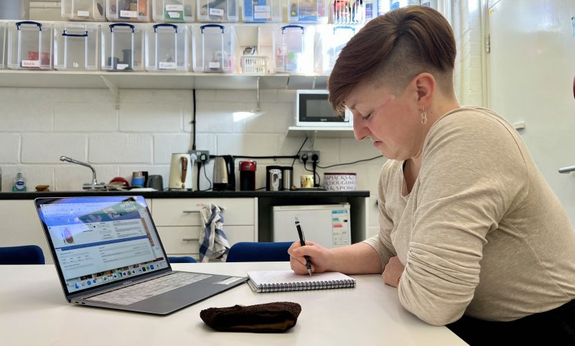 A Collections Assistant writes in a notepad in front of an open laptop