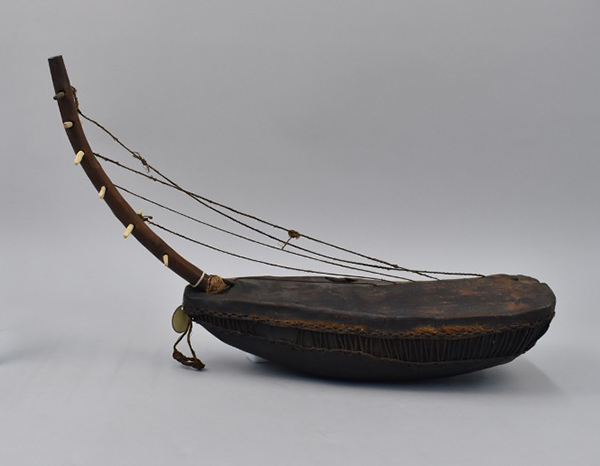 Dark brown musical instrument object, set against a grey studio background.