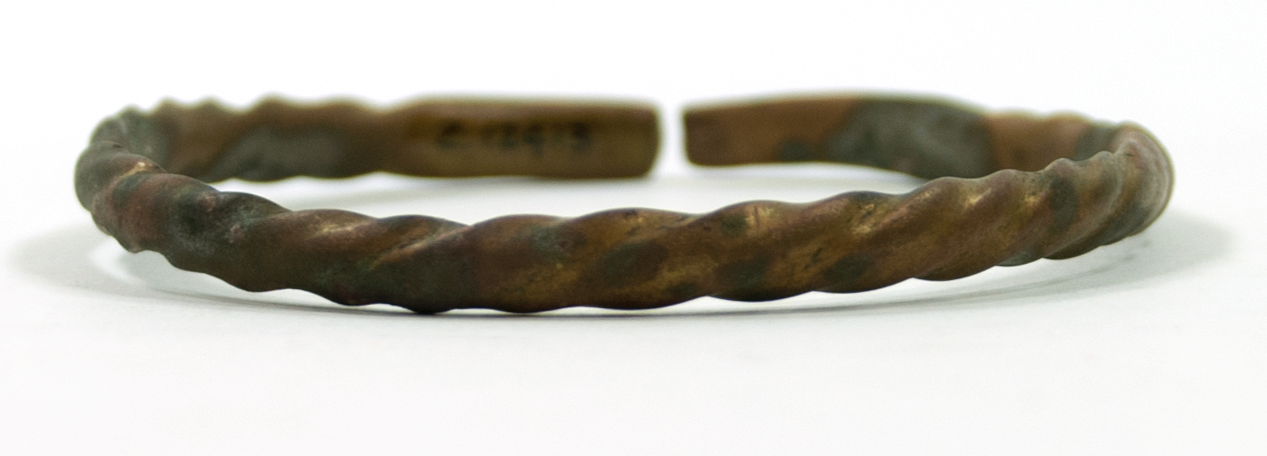  Twisted brass bracelet, with flattened ends. Shown on its side.