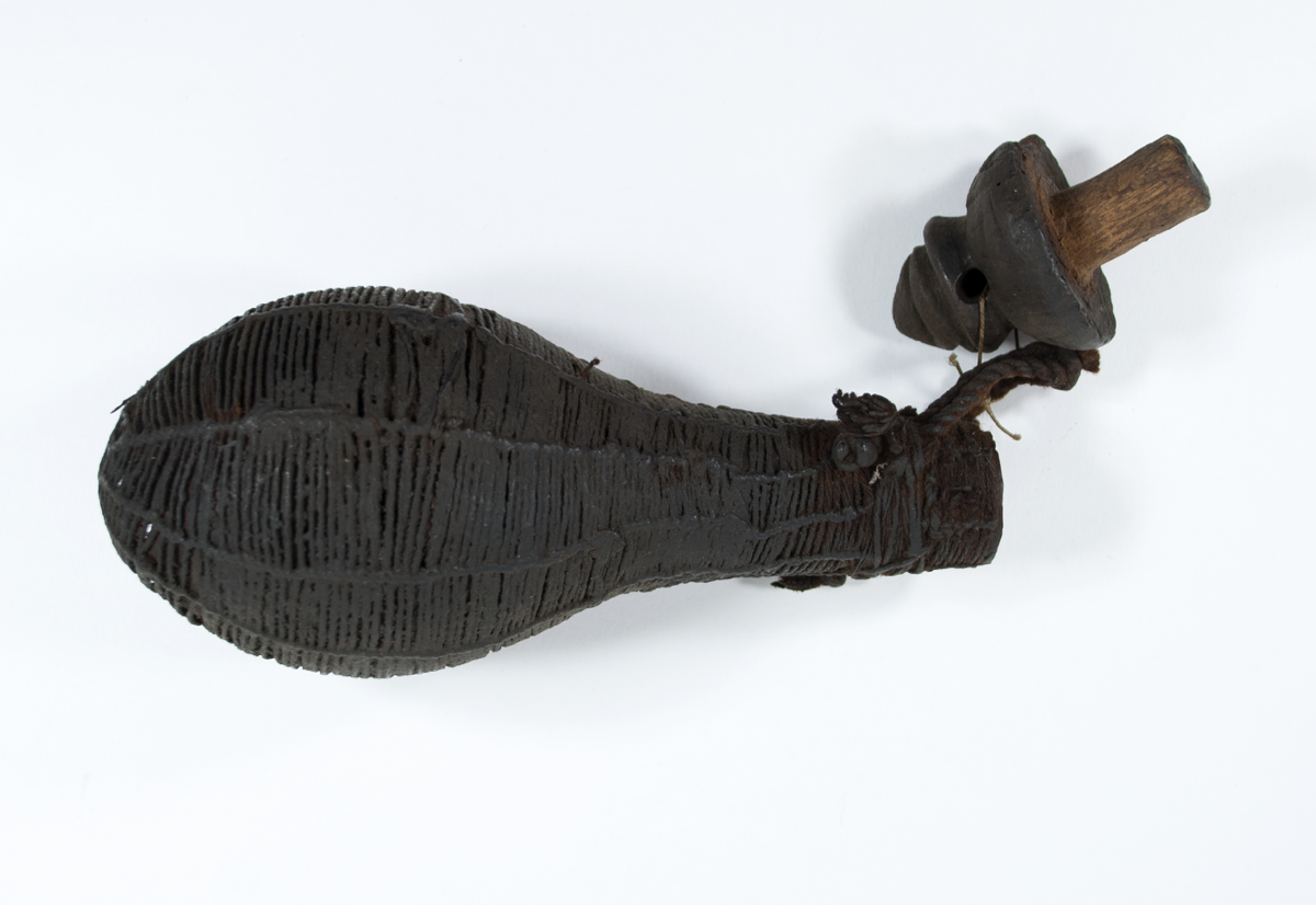 Medicine bottle wrapped in cord with a carved, conical shaped, wooden stopper.