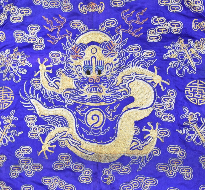 Detail from a blue silk robe decorated with a goldwork dragon.