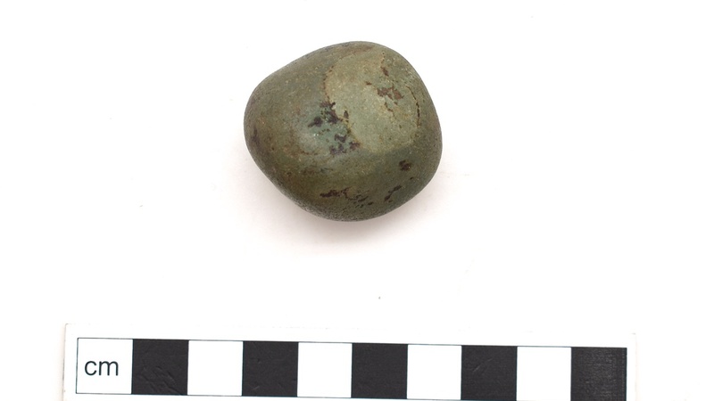 Small stone, green and roughly circular, photographed against a studio background.