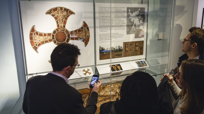 Visitors look at items in the Clarke Gallery. One man is holding a phone with the camera open.