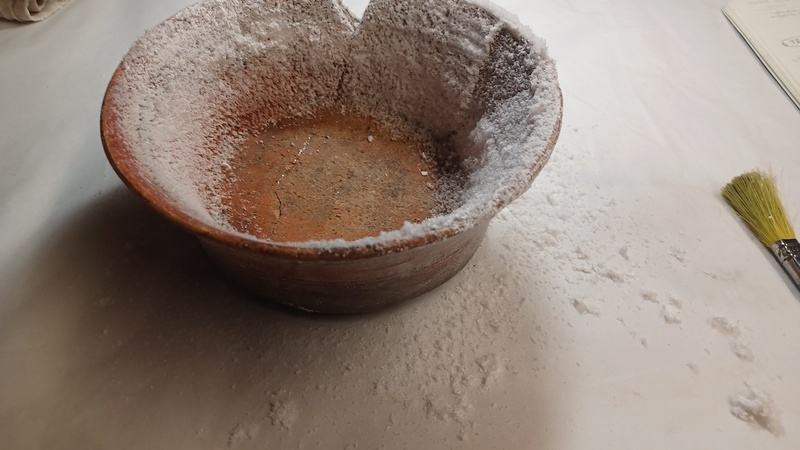 A terracotta bowl, the internal sides of which are heavily coated in crystals.