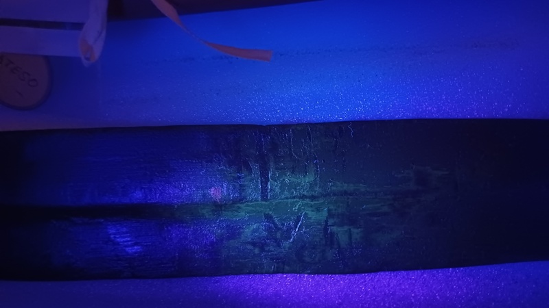 Detail of a section of a double edged blade under a UV light revealing a yellowish colour indicating it has been covered in beeswax.
