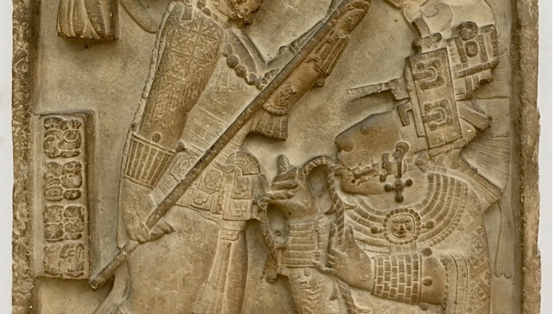 A stela detailing two figures engaged in a blood letting ceremony. They are wearing regal clothes and headdresses.