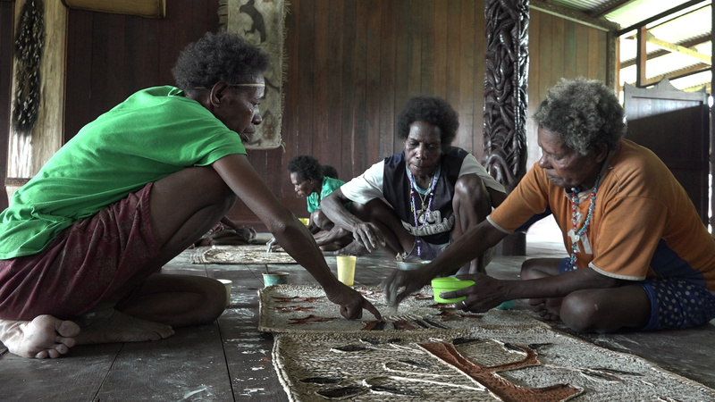 Ravaela Ep directs Virginia Tómbair and Bibiana Kákan in the painting of a pir mat for the museum.