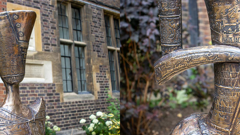 Two side by side detail photographs of the sculpture. The head (left) has a script panel, with the carved word 'MAORI' visible at the bottom. The arms and body (right) have mostly script and writing across them, which look like they come from a newspaper.