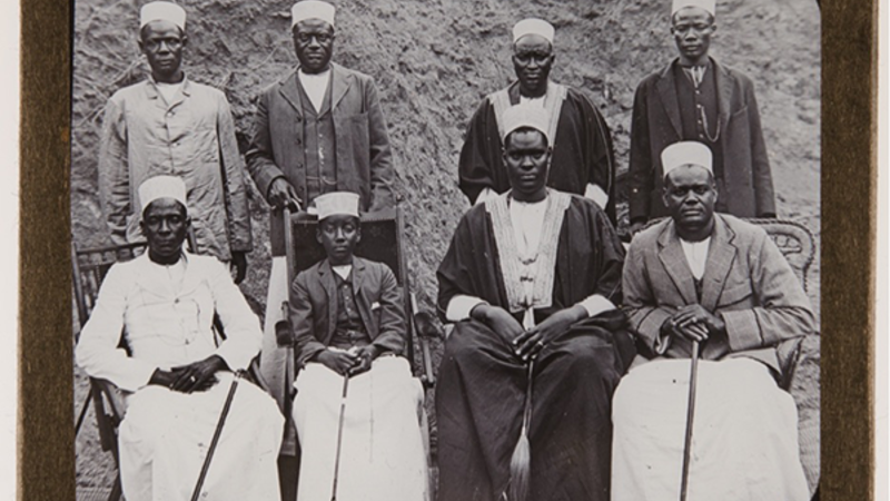 Sepia photograph with eight men, four sitting and four standing, within a paper frame. Wording: 'Rulers &amp; Prime Ministers'. 'Cambridge Museum of Archaeology and Ethnology'