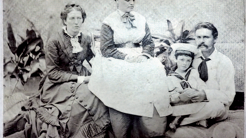Black and white photograph of three adults and a child, posing in seated positions.