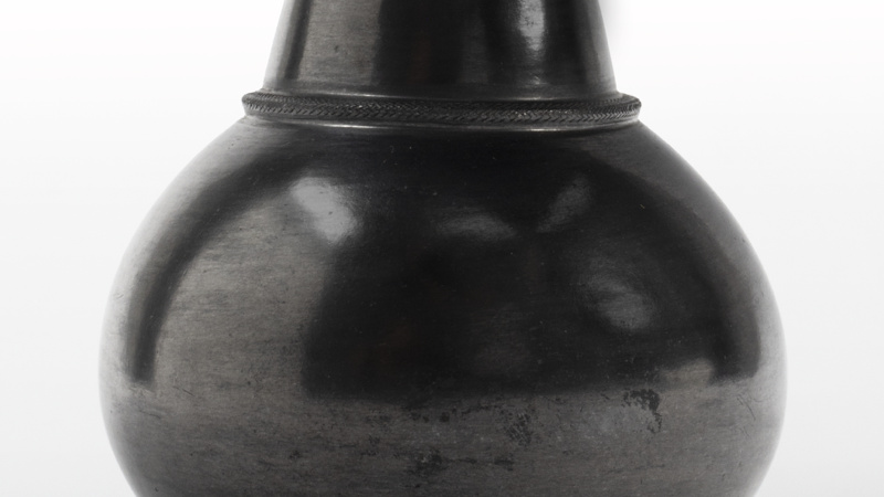 A pot with a narrow, everted rim, a tapering neck, globular body and rounded base. The outer body of the vessel has a reflective, dark grey glaze.