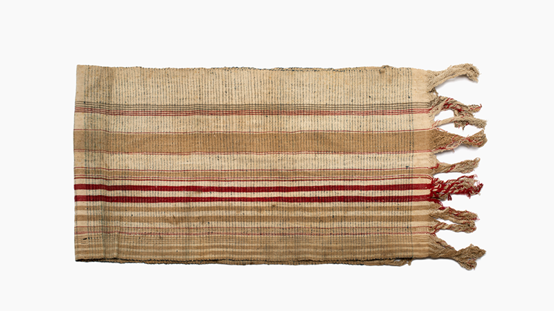 Striped piece of cloth in beige, brown and red. There are long fringes on both short edges.