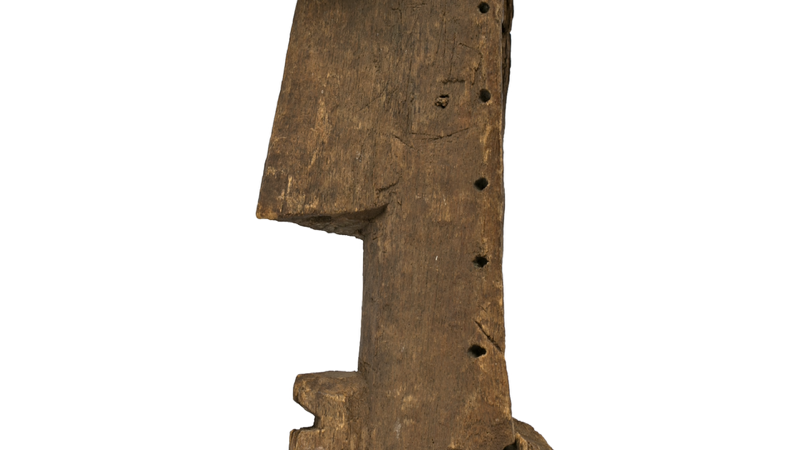  Roughly carved wooden mask with prominent nose and mouth. The face is long and thin, with a slightly elongated chin.