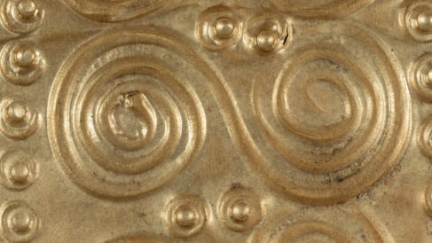 Detail of one of the embossed double spirals which decorate an oval-shaped sheet of thin gold.