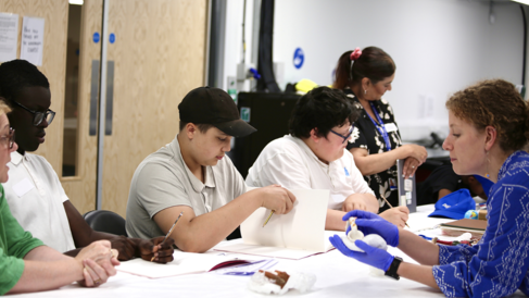 A Education and Outreach Assistant shows objects from the collections to a group of young people with special educational needs and disabilities (SEND).