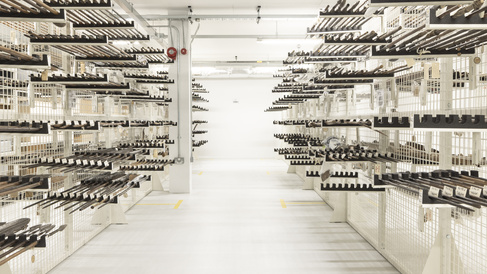 Wire racking within the museum's off-site store which holds rows of spears. Each group of around six spears lie horizontally across brackets that protrude from the racking and are supported near both ends.